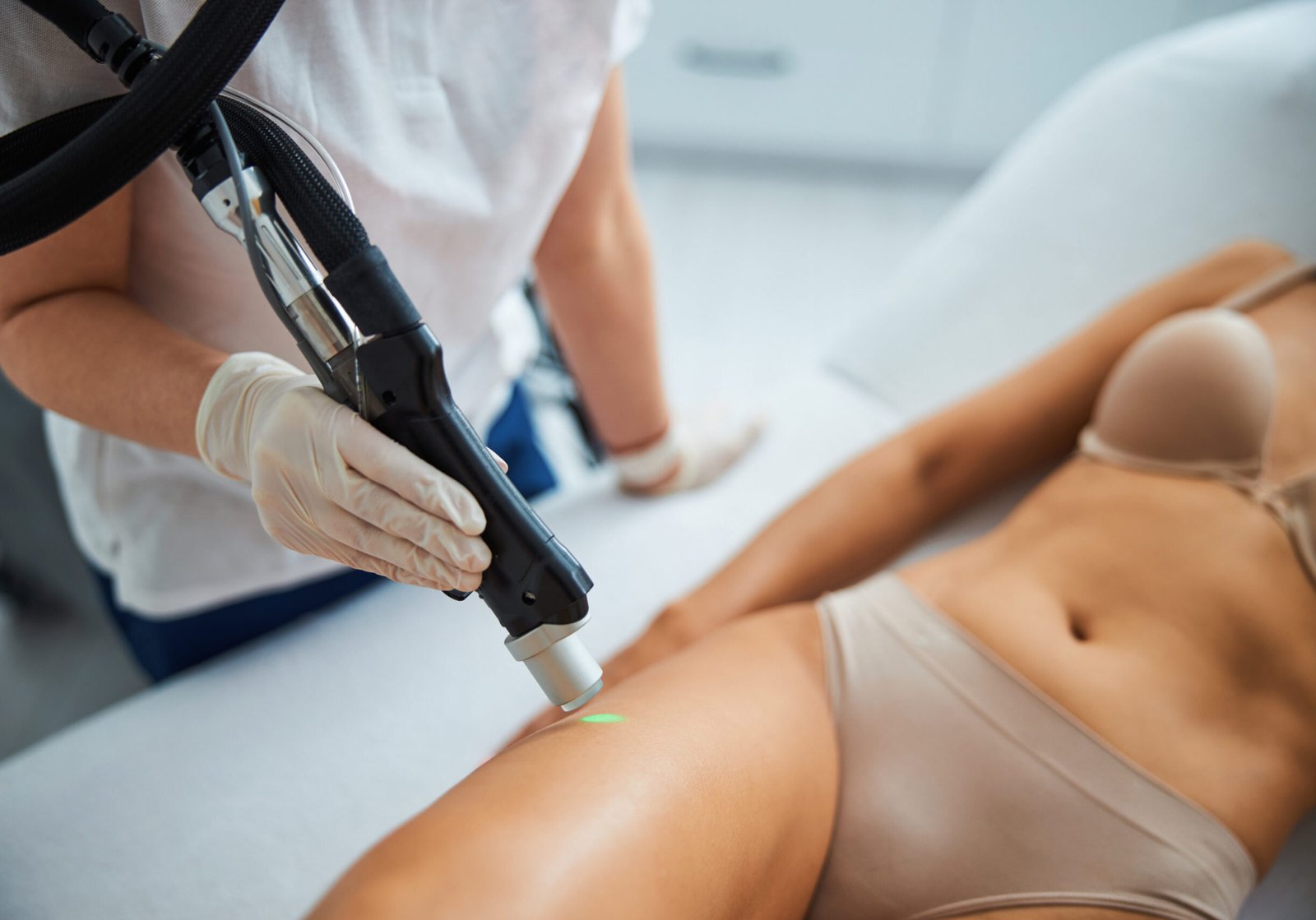 Beautician performing a hair removal procedure on the upper thigh Cropped photo of a skilled cosmetologist directing a laser beam at the female patient leg
