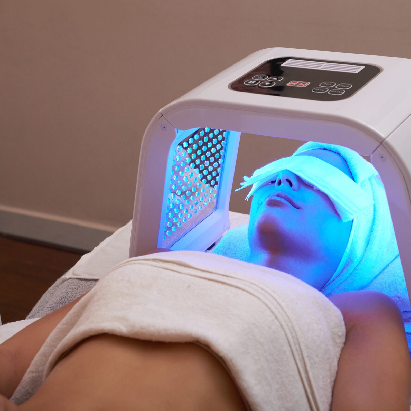 Young woman having LED light facial treatment in beauty salon